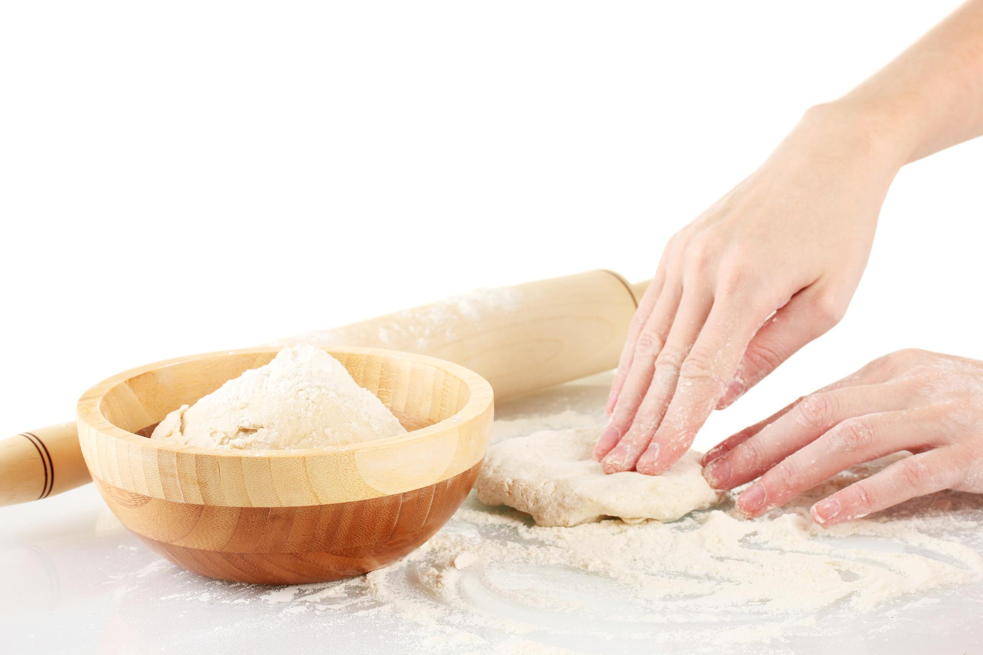 hands kneading dough on wooden table